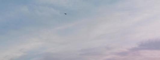 blaue und rosa Wolken am Himmel. Hubschrauber fliegt weit. foto