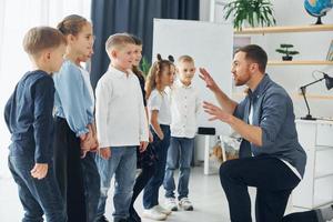 Geschichtenerzähler mit interessanten Informationen. gruppe von kinderschülern im unterricht in der schule mit lehrer foto