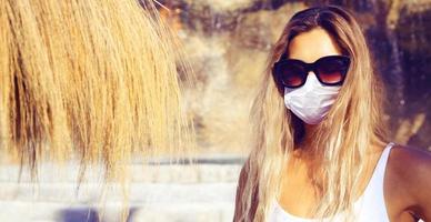 schöne touristenfrau mit koronavirusmaske am strand foto