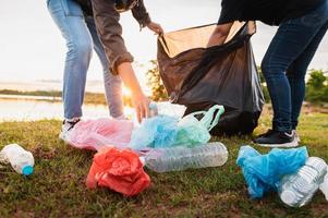 frauenhand, die müllplastiktüte zur reinigung im park aufhebt foto