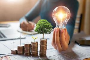Geschäftsmann mit Glühbirne mit Turbine und Baum wachsen auf Münzen. konzept zur energieeinsparung und finanzbuchhaltung foto