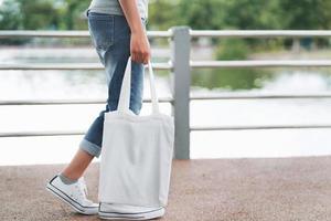 Hipster-Frau mit weißer Baumwolltasche im Park foto