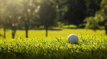 Golfball auf grünem Gras mit Sonnenlicht foto