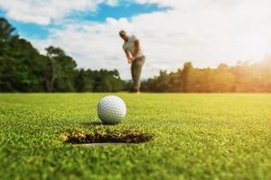 Golfspieler, der Golfball ins Loch setzt foto