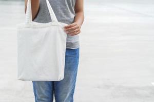 hipster-frau, die weiße einkaufstasche für mock-up-leere vorlage hält foto