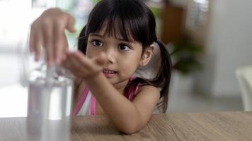Kleines asiatisches Mädchen legte eine Alkohol-Gel-Desinfektionspumpe auf die Hände, um sie zu reinigen oder sich die Hände zu waschen. foto