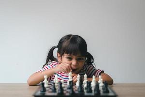 asiatisches kleines mädchen, das zu hause schach spielt. ein schachspiel foto