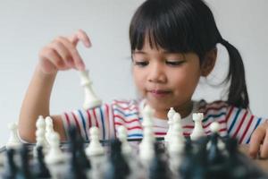 asiatisches kleines mädchen, das zu hause schach spielt. ein schachspiel foto