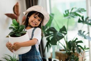 Topfpflanzen zu Hause, die von einem süßen Kind gehalten werden foto