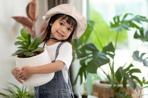 Topfpflanzen zu Hause, die von einem süßen Kind gehalten werden foto
