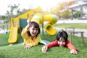 Kind spielt auf Spielplatz im Freien. kinder spielen auf dem hof der schule oder des kindergartens. aktives kind auf bunter rutsche und schaukel. gesunde sommeraktivität für kinder. kleines Mädchen, das draußen klettert. foto