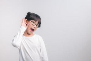 Kleines asiatisches Mädchen hält ihre Hand in der Nähe ihres Ohrs und hört zu. Tag der Behinderung. taubes Kind. aufregendes Gesicht auf asiatischem Kindermädchen. Schalten Sie das Telefon aus und hören Sie Ihrem Kind zu. foto
