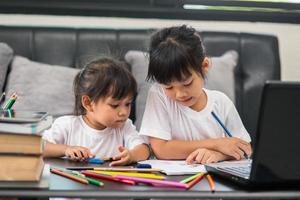 covid-19 coronavirus und lernen von zu hause aus, konzept für hausschulkinder. kleine kinder lernen online von zu hause aus mit laptop. foto