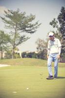 Golfspieler auf dem Putting Green, der den Ball in eine hole.vintage-Farbe schlägt foto