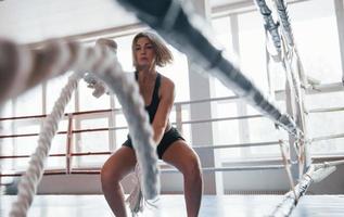 vor dem Boxen. Blonde Sportlerin trainiert mit Seilen im Fitnessstudio. starkes Weib foto
