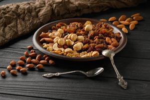 Haselnüsse, Cashewnüsse, Rosinen, Mandeln, Erdnüsse, Walnüsse auf schwarzem Holzhintergrund foto