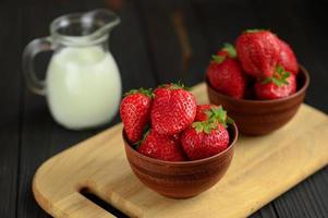 eine schüssel mit roten saftigen erdbeeren auf rustikalem holztisch. gesundes und diät-snack-food-konzept. foto