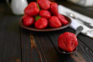 eine schüssel mit roten saftigen erdbeeren auf rustikalem holztisch. gesundes und diät-snack-food-konzept. foto