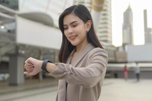 geschäftsfrau verwendet intelligente uhr in der modernen stadt, geschäftstechnologie, stadtlebensstilkonzept foto