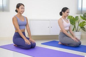 fitte junge freundinnen, die zu hause yoga und meditation machen, sport und gesundes lebensstilkonzept. foto