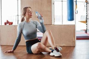 frisches Wasser trinken. Sportliche junge Frau hat morgens einen Fitnesstag im Fitnessstudio foto