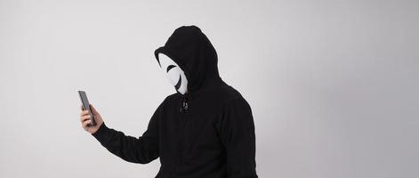 Anonymer Hacker und Gesichtsmaske mit Smartphone in der Hand. foto