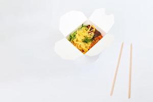 Reiswok in Box und Holzstäbchen isoliert auf weißem Hintergrund, asiatische Lebensmittellieferung, Kopierraum foto