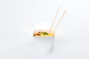 Reiswok in Box und Holzstäbchen isoliert auf weißem Hintergrund, asiatische Lebensmittellieferung, Nahaufnahme foto