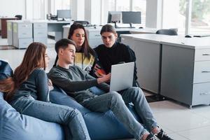 gucken Sie, was ich gefunden habe. Gruppe junger Menschen in Freizeitkleidung, die im modernen Büro arbeiten foto