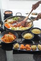 tokboki koreanisches traditionelles essen heißer und würziger reiskuchen, kombination und puff mit käse und gemüse auf dem schwarzen tisch auftragen foto