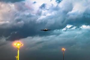Flugzeug hebt in der Nacht mit dunklem bewölktem Himmel vom Flughafen ab. foto