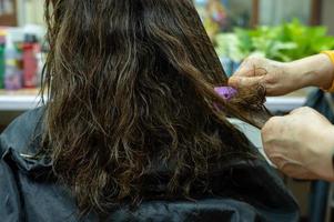 Friseur schneidet und trimmt Kundenhaare von hinten. Ein Friseur ist eine Person, die sich auf das Färben, Schneiden und Stylen von Haaren spezialisiert hat. foto