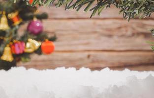Weihnachtsrahmen mit unscharfem Weihnachtsbaum und Ornamenten und Schnee und Holzhintergrund, Kopierraum foto