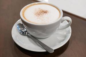 schaumiger kaffee und edelstahllöffel werden im café auf den tisch gestellt.selektiver fokus foto