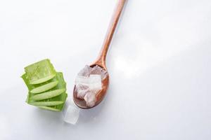 aloe vera gel auf holzlöffel mit aloe vera auf weißem hintergrund, aloe vera ist tropische grüne pflanzen. in scheiben geschnittene aloe vera natürliche organische erneuerungskosmetik, alternative medizin. Bio-Hautpflegekonzept. foto