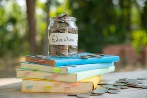 Einlegen von Geldmünzen, die in einer Glasflasche für die Finanzierung und das Geschäft von Konzeptinvestitionen in Investmentfonds sparen, die in das Lehrbuch aufgenommen wurden. Inhalt Geld sparen für Bildung. foto