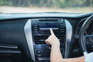 Hand einer Frau, die das Auto-Klimasystem einschaltet, Knopf auf dem Armaturenbrett im Auto-Panel, Auto-Auto-Klimaanlage Auto-Armaturenbrett. Radio-Nahaufnahme. Frau stellt Radio auf. foto