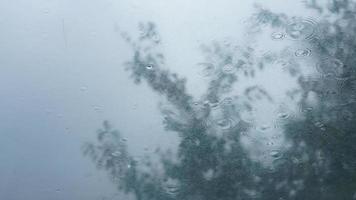das glasfenster, das am regnerischen tag von den regentröpfchen und dem wasserfall bedeckt ist foto
