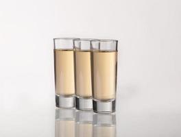 drei goldene Tequila-Aufnahmen mit Limette auf weißem Hintergrund foto