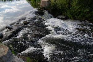 Ein kleiner Flusswasserfall an einem hellen, sonnigen Sommertag. foto