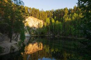 Bergsee mit Spiegelung im Wasser vor dem Hintergrund des Waldes und der Strahlen der untergehenden Sonne. foto