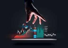 Geschäftsmann zeigt Hand für Online-Diagramm der globalen Aktienmarktinvestitionen auf dem Tablet. foto