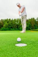 vertikaler Bildmann, der Golf auf einer grünen Wiese spielt foto