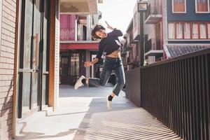 glückliche junge asiatische frau, die musik hört und spaß mit kopfhörern auf der straße hat foto