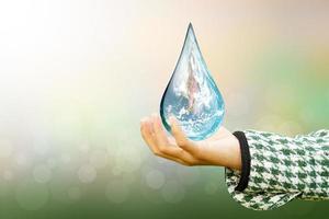 weltwassertag hände, die auf die welt in wassertropfenform auf hintergrund warten, verschwommene blumen und himmel mit dem licht der sonne. elemente dieses bildes, bereitgestellt von der nasa. foto