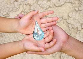 Weltwassertaghände, die auf die Welt in Wassertropfenform auf trockenem Boden warten. elemente dieses bildes, bereitgestellt von der nasa. foto