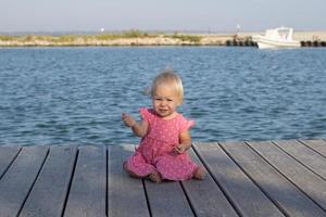 kleines Mädchen in rosafarbenem Kleid in der Nähe des Flusses foto