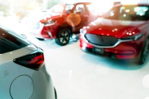 Verwischen Sie das rote und weiße Auto, das im Luxusausstellungsraum geparkt ist. autohaus büro. neues Auto in modernem Ausstellungsraum geparkt. auto für verkauf und miete geschäftskonzept. Autoleasing und Versicherungshintergrund.