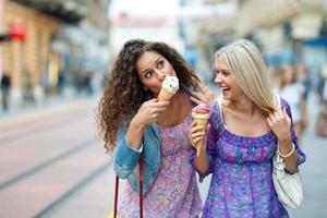 zwei jugendlich Mädchen, die Eis in Blumenkleidern essen