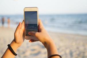 frau, die foto der strandlandschaft mit intelligentem telefon macht